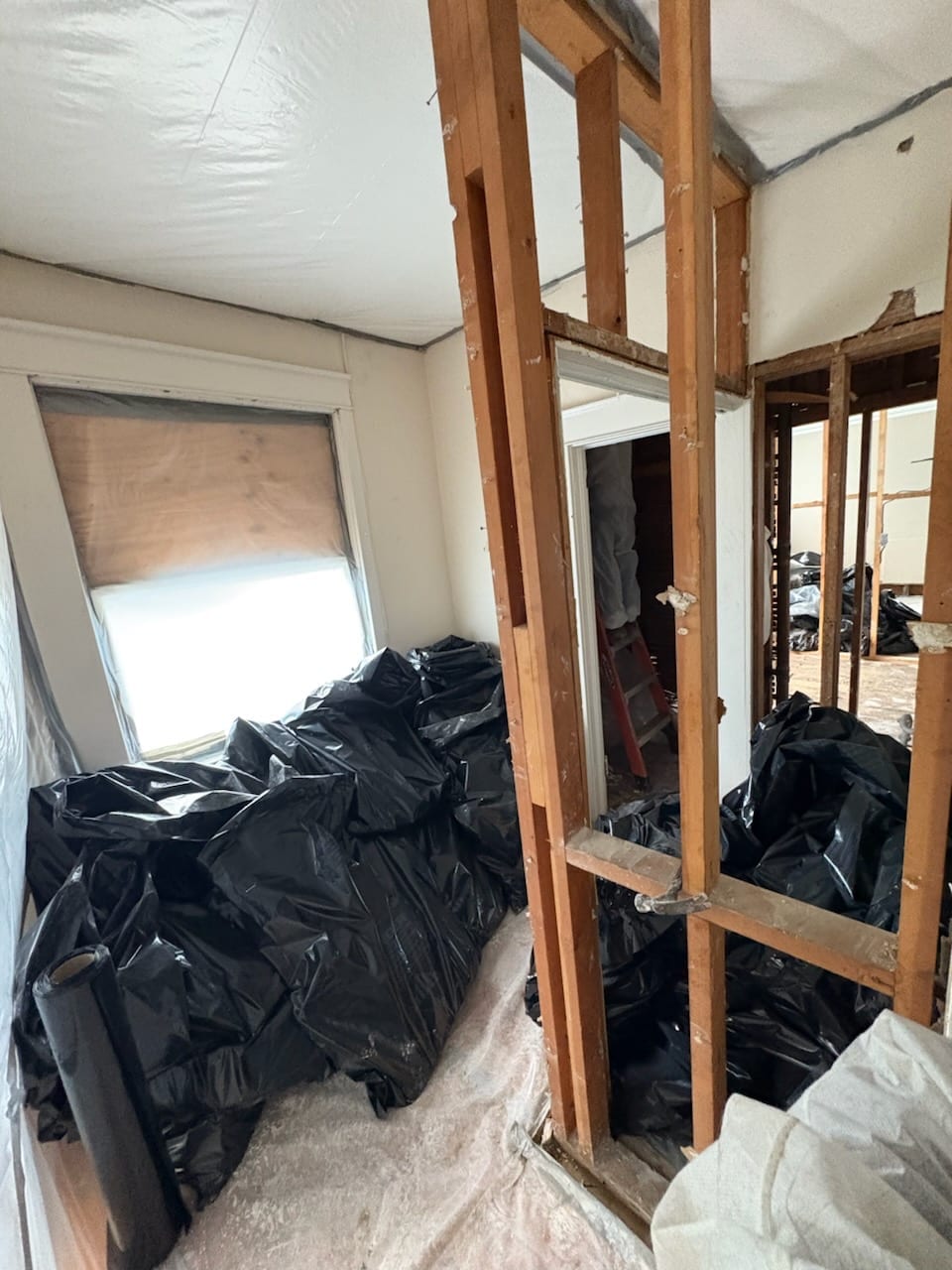 Room inside a plastic containment, filled with bagged asbestos waste awaiting disposal